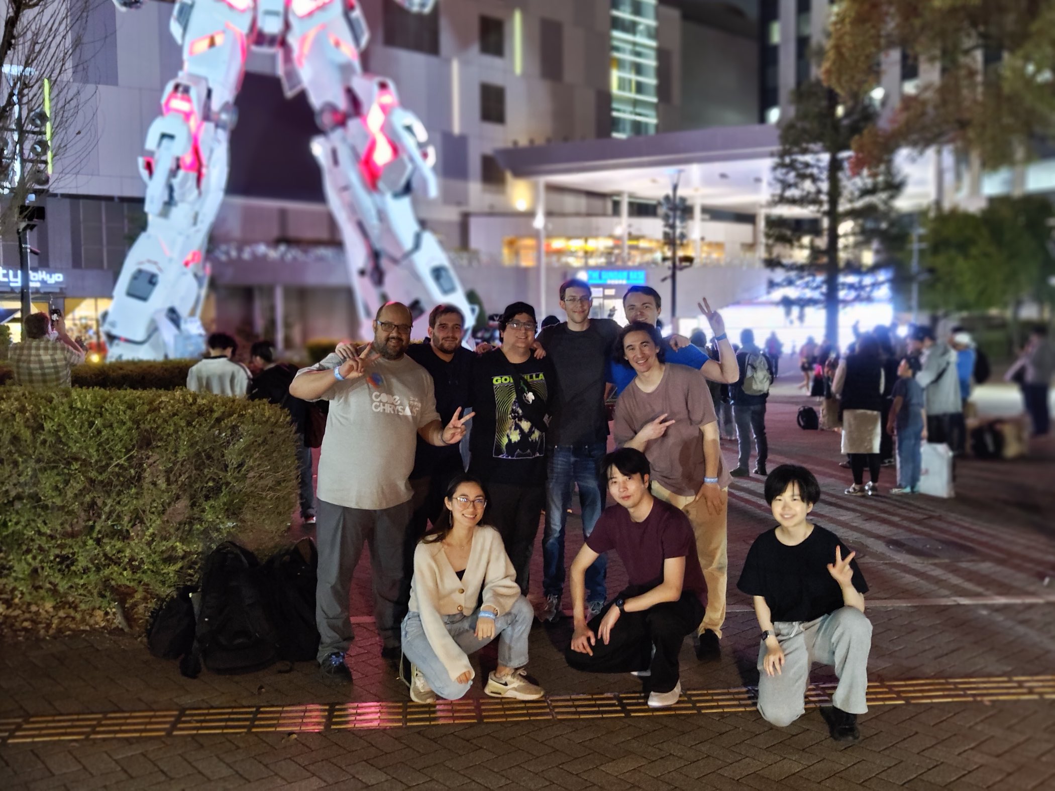 Matt and his cohort posing together at night in front of the illuminated Unicorn Gundam statue in Odaiba, Tokyo
